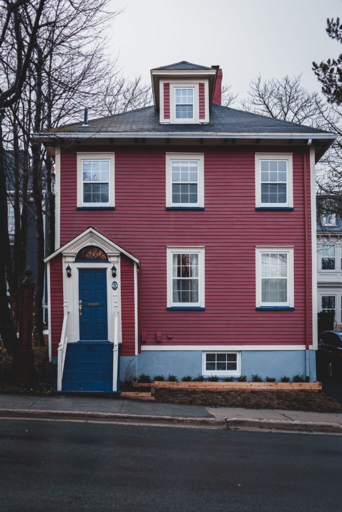Exterior of residential house with blue door and stairs and crimson color walls